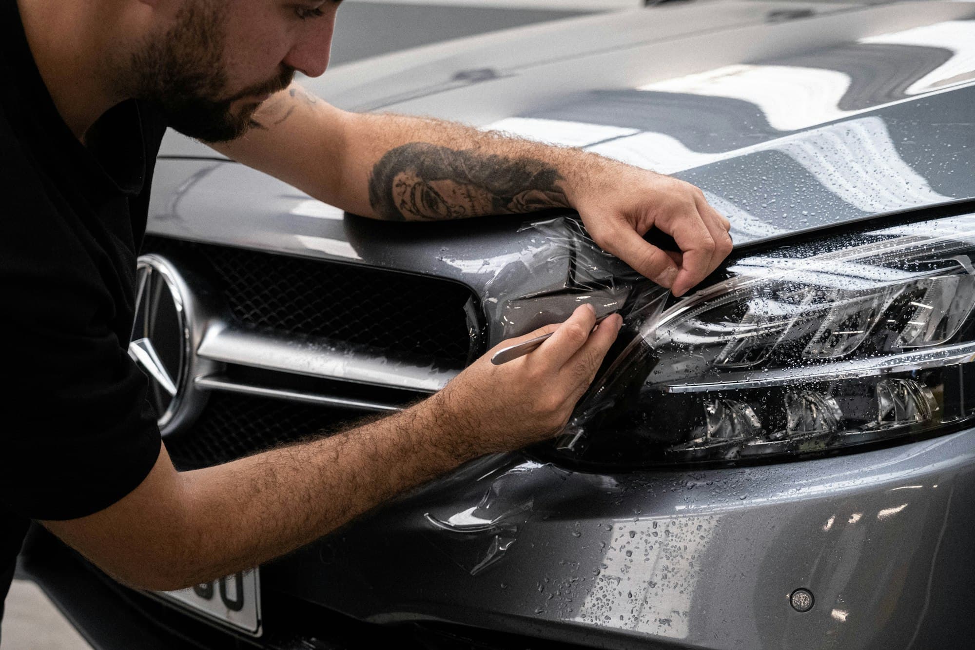 Detailer hand-waxing the hood of a car